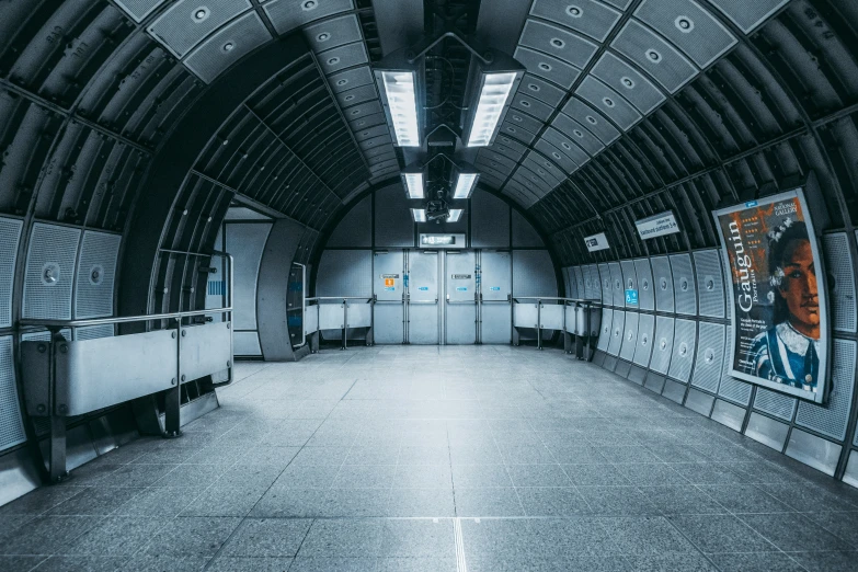 the inside of an empty subway station with posters