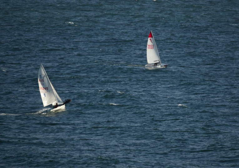 two small sailboats are traveling across the water