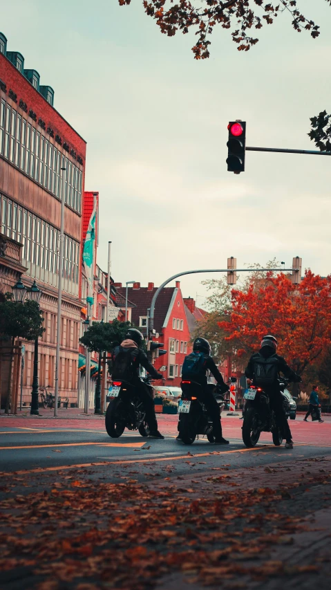 three motorcyclists are stopped at a stop light in a busy street