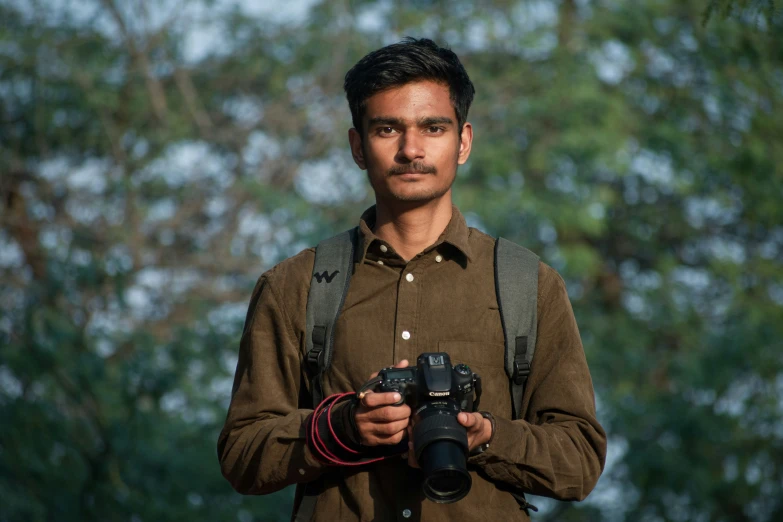 a man holding a camera posing for a po