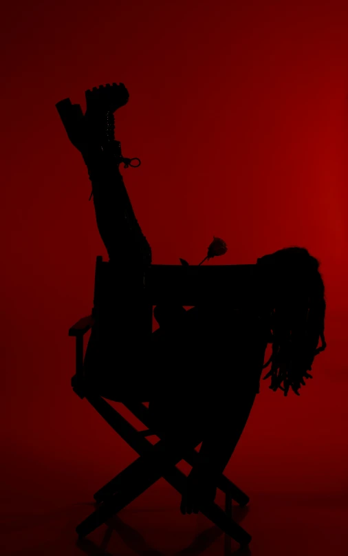 the silhouette of a woman sits in a chair