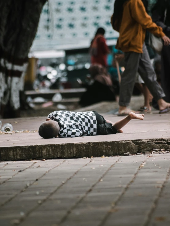 a small boy laying on the street with his arms extended