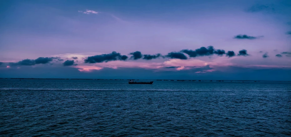 a boat floating on top of the ocean at dusk