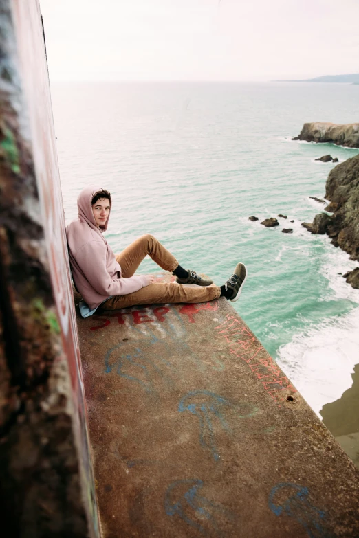 man sitting on pier overlooking ocean in urban setting