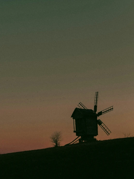 a windmill in the middle of a field at sunset