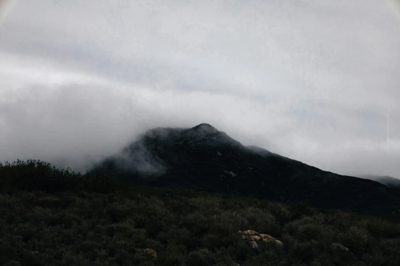 a mountain scene with cloudy skies and clouds