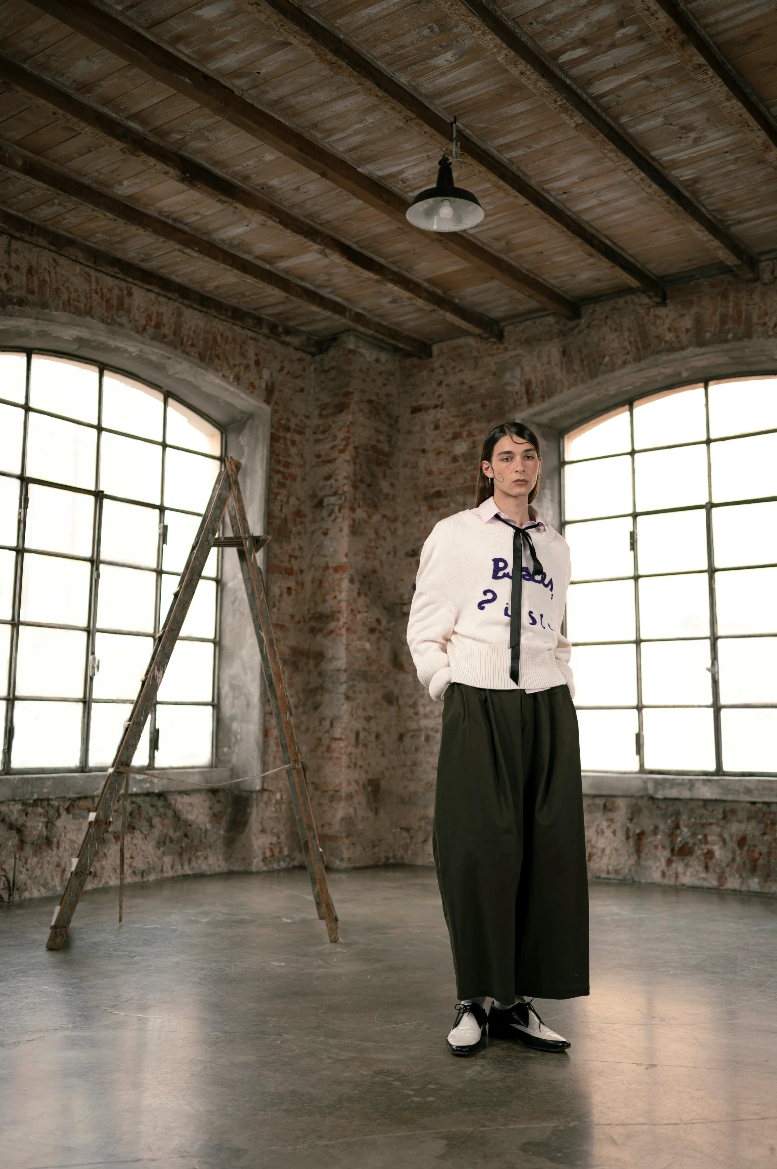 the young person stands next to two windows