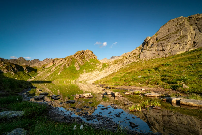 a body of water on a rocky hill covered in grass and rocks