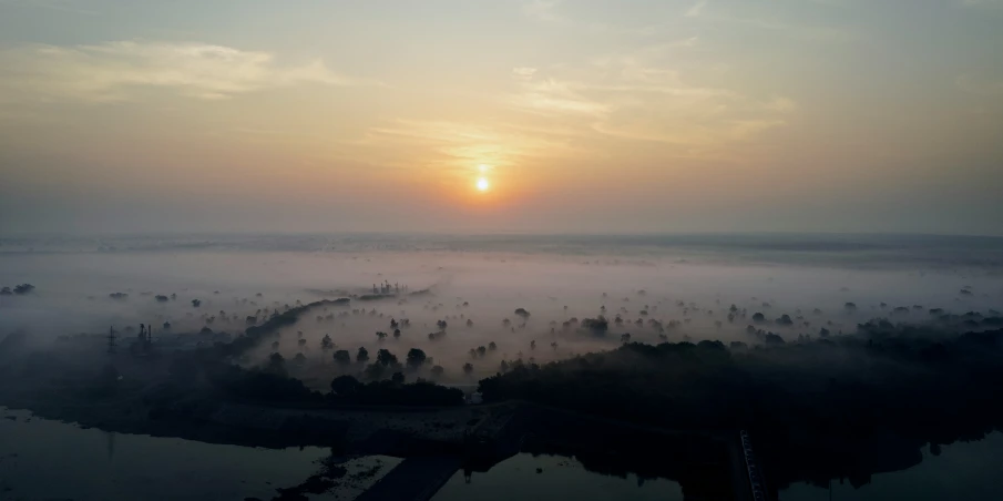 sun set in fog over lake and small town