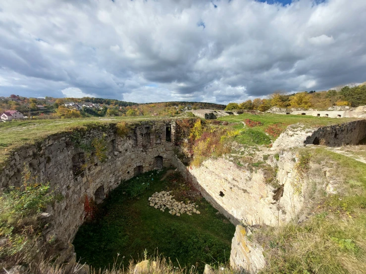 an ancient rock cut tunnel surrounded by grass and clouds