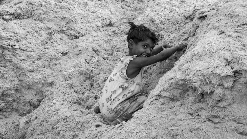 a boy climbs up out of the sand in this black and white po