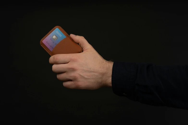 a person holding onto a wallet on black background