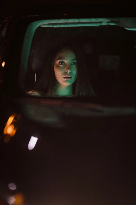 a woman looks at herself in a car window