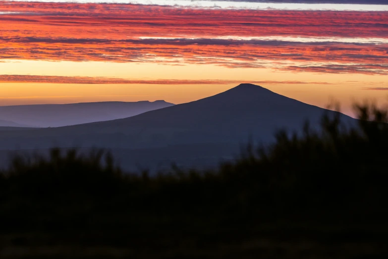 the sun setting over the mountain with some red clouds