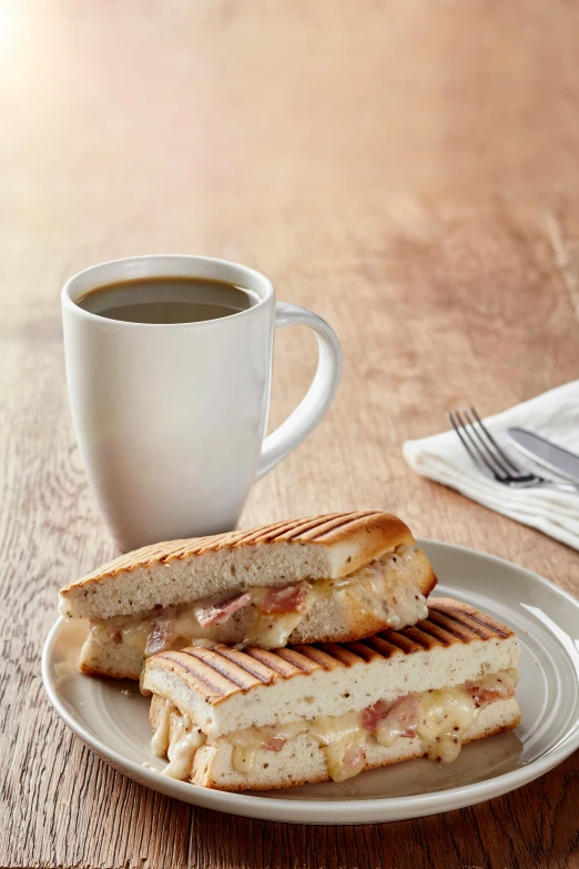 a cup of coffee and some toasted sandwiches on a plate