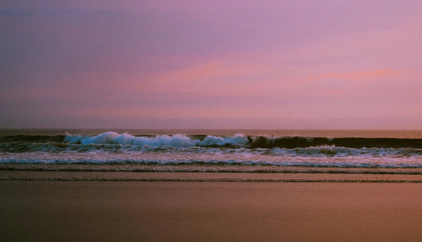 surfers walking on the beach in front of waves