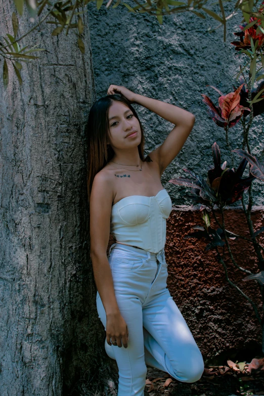 a woman is leaning on a tree trunk