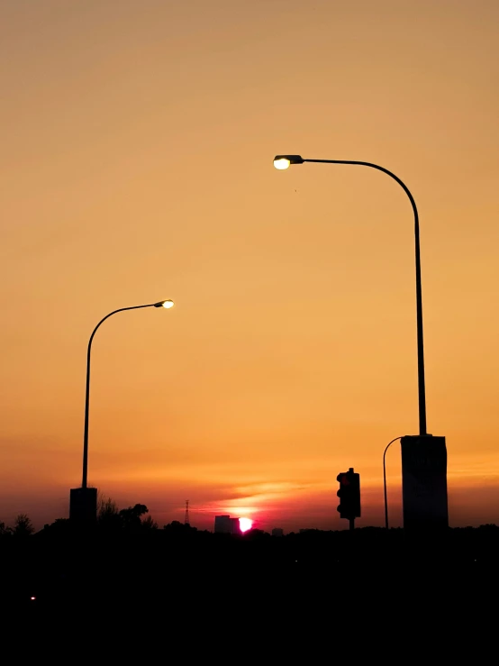 three street lights on an overpass at sunset