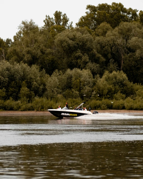 a black and white boat in the water with trees in the background
