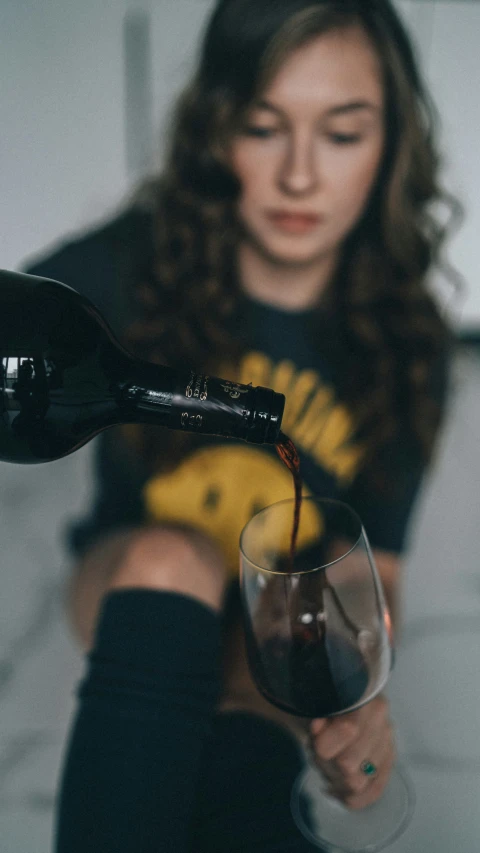 a woman sitting on the floor pouring wine in a glass