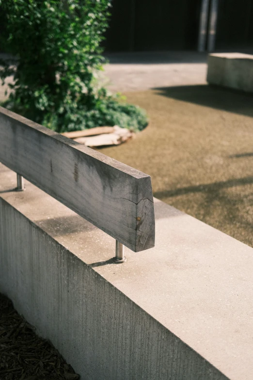 a wooden bench sits in the sun next to an empty planter