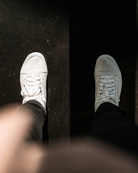 a person with white shoes stands on a black surface