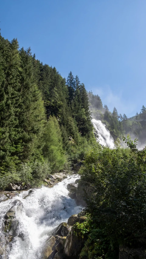 a mountain falls down into the river that's surrounded by trees