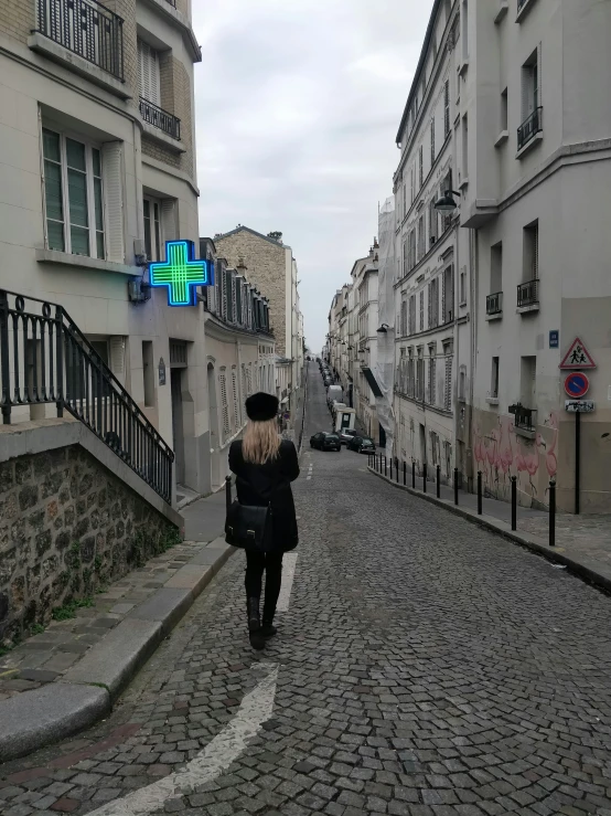 a woman walking down a cobblestone road next to buildings