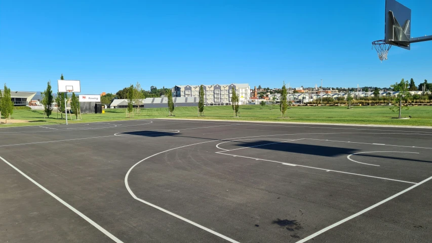an empty basketball court and net with lots of grass