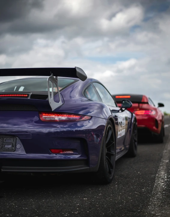 a blue sports car driving down a road next to another red car