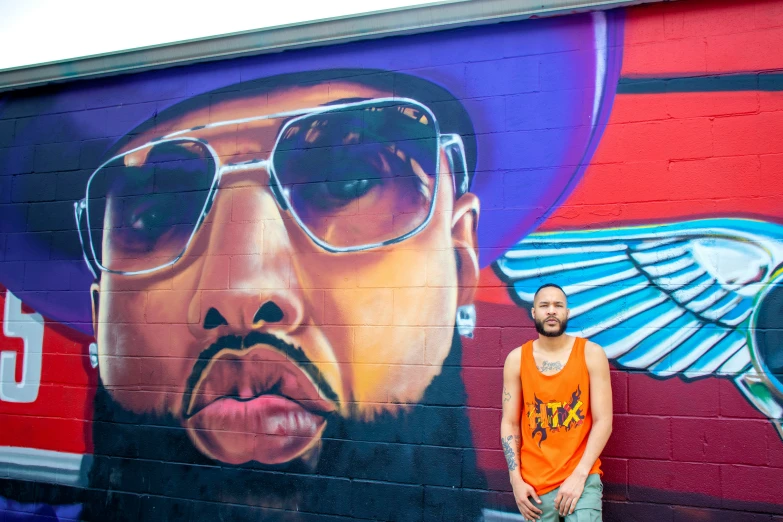 a young man standing next to a colorful wall mural