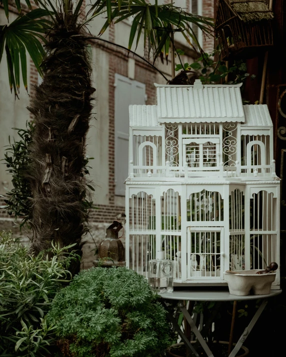 a white birdhouse next to a palm tree in the garden