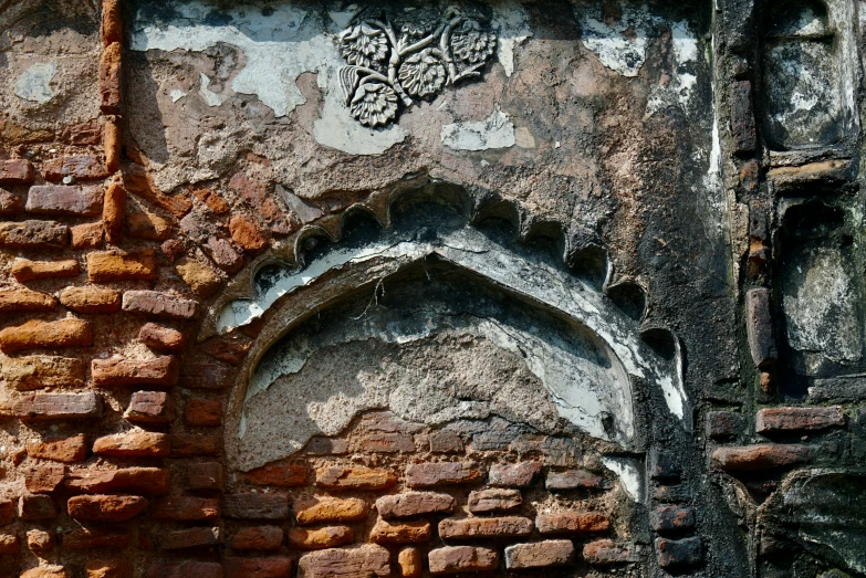 the view from a distance, looking up at an old building wall with brick pillars and a carving on one end of the side