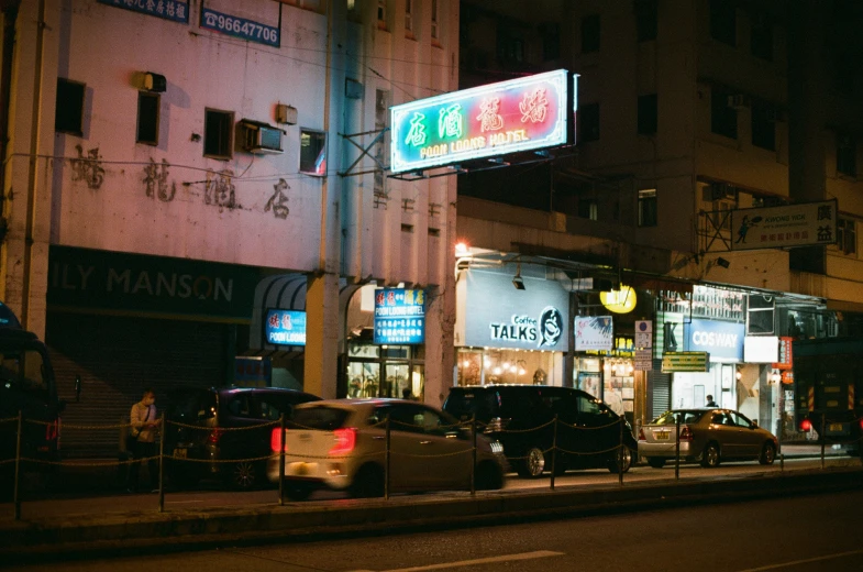 a chinese street with cars parked on the side and a store sign hanging above