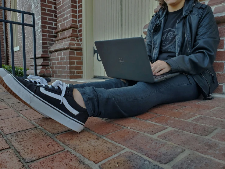 a woman sits on the ground using her laptop