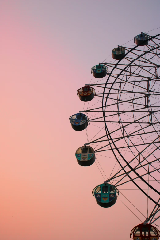 a ferris wheel flying over a pink sky