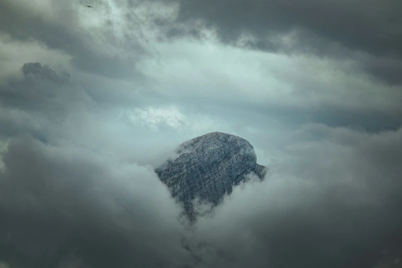 a large mountain sitting in the clouds on a gloomy day