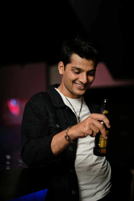 a man is holding a bottle in his hand and smiling