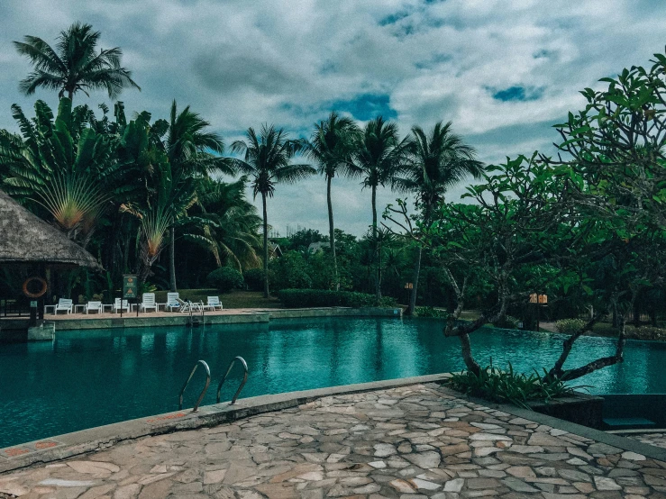 a stone paved pool with trees and grass