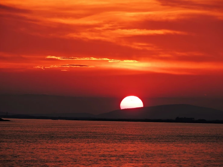 a bright orange sky is shining over a bay