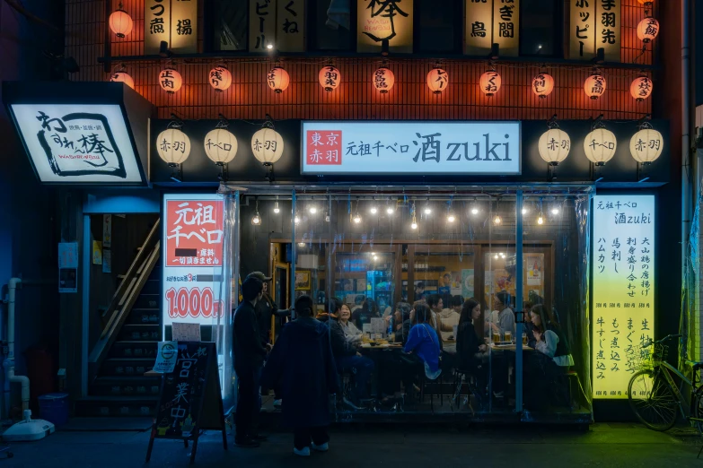 an asian restaurant front at night with people ordering