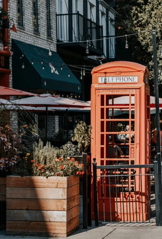 an orange public phone booth sitting in a courtyard