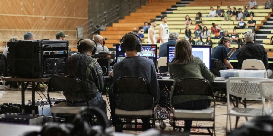 three people in an auditorium playing video games