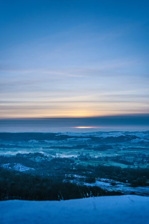 the sun rises over a snow covered hillside