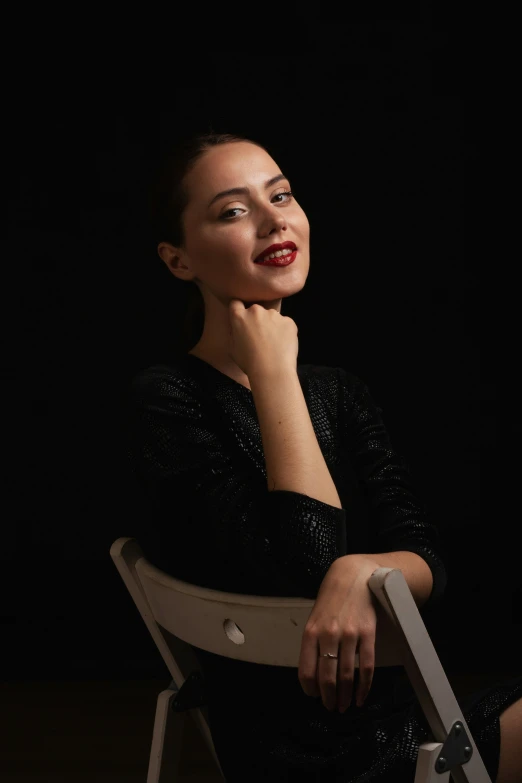 a woman sitting on a white chair posing for a po