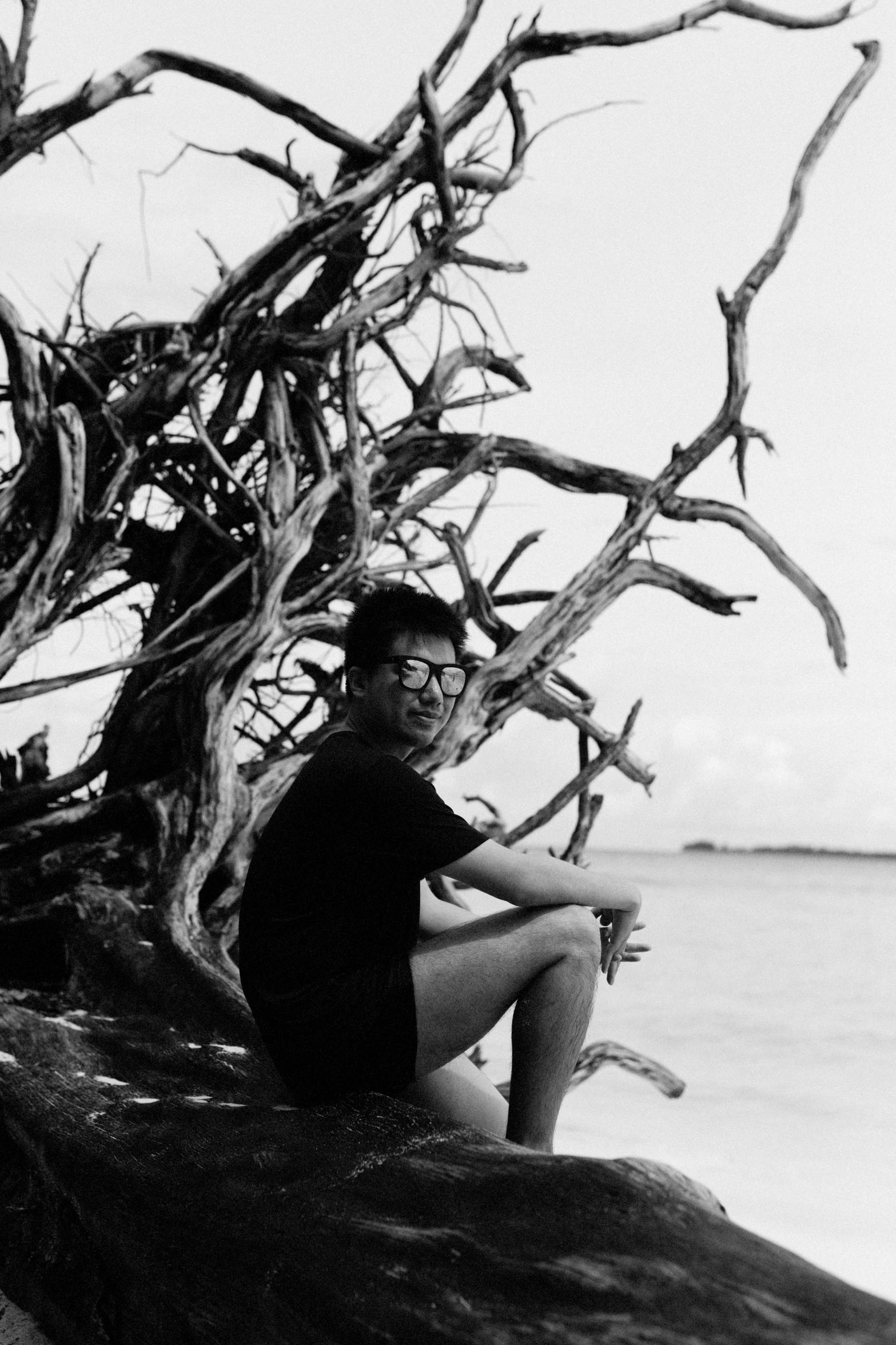 a man is sitting on the beach by the water