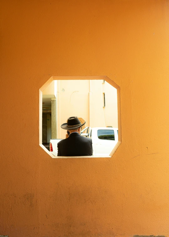 a man sitting in front of a window with a cowboy hat on