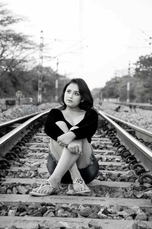 a girl is sitting on a railroad track posing for a po