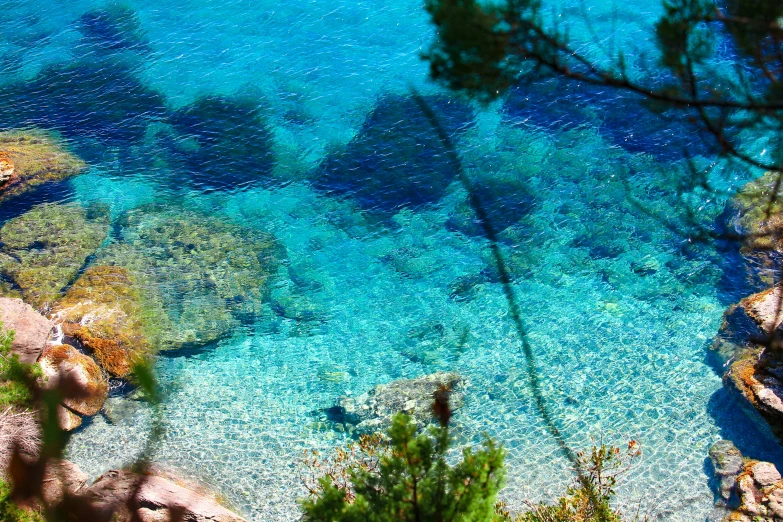 blue green water and some rocks are pictured