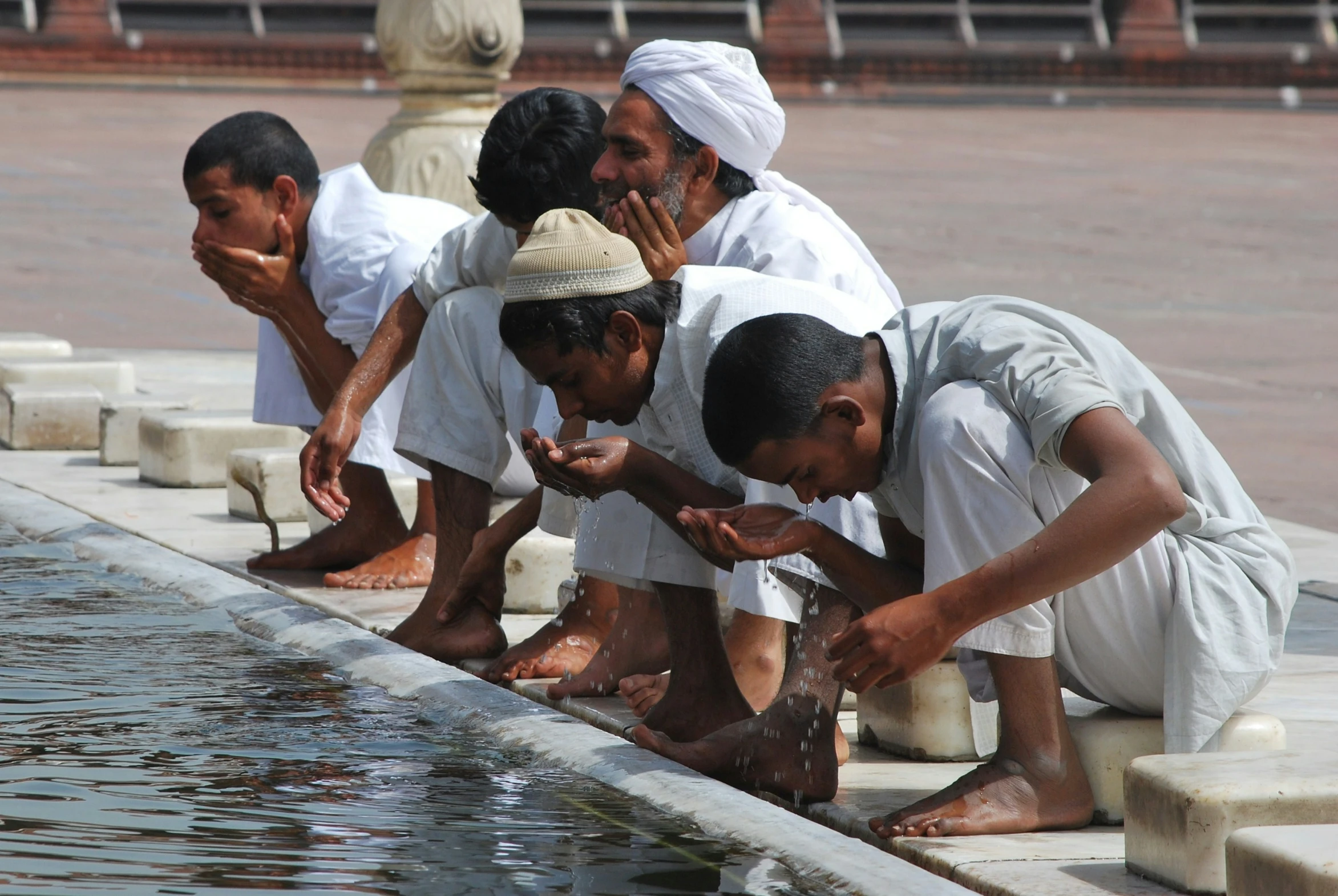 five men are kneeling down by the water